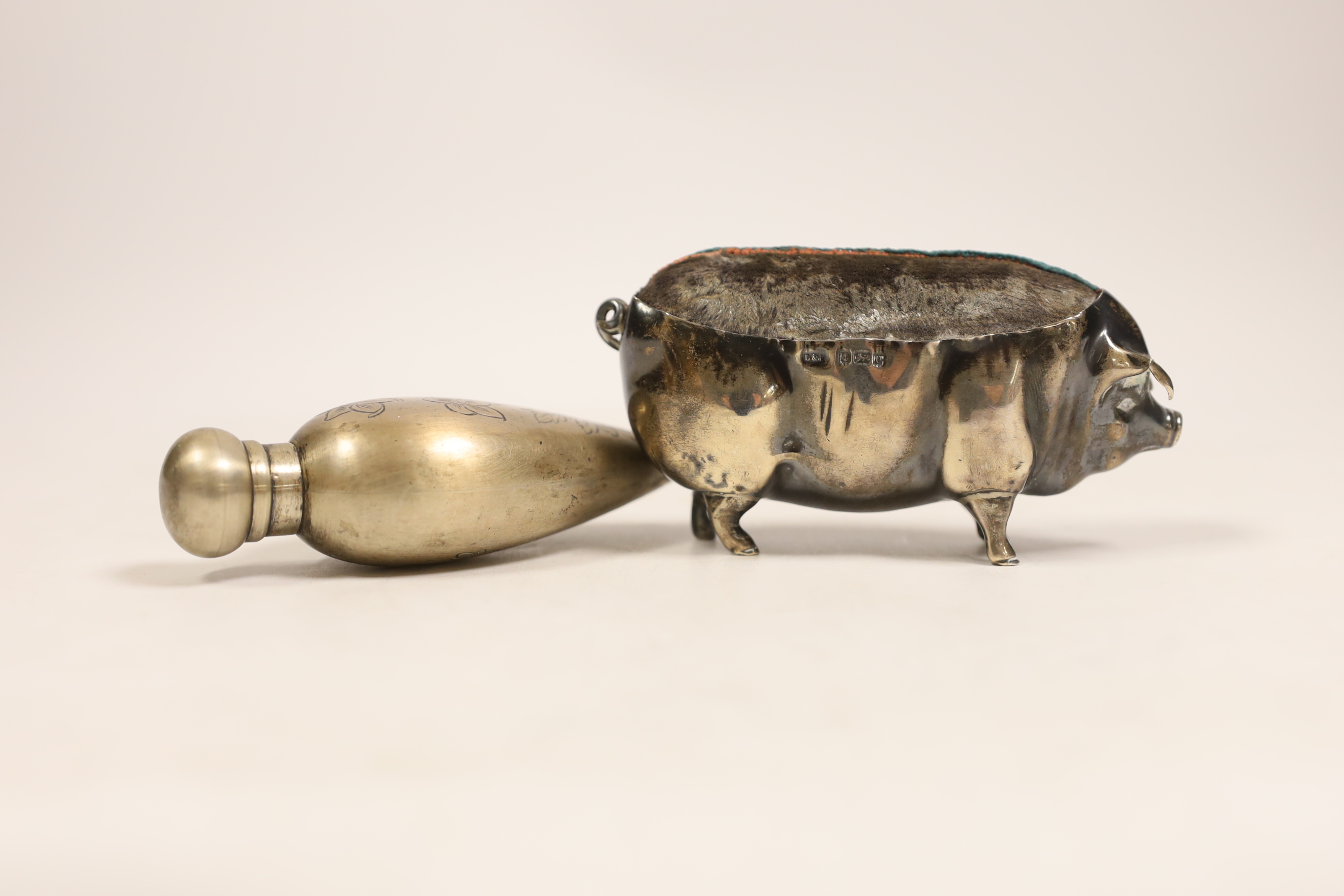 A large Edwardian silver mounted pig pin cushion, Levy & Salaman, Birmingham, 1904, length 10.5cm, together with a scent bottle.